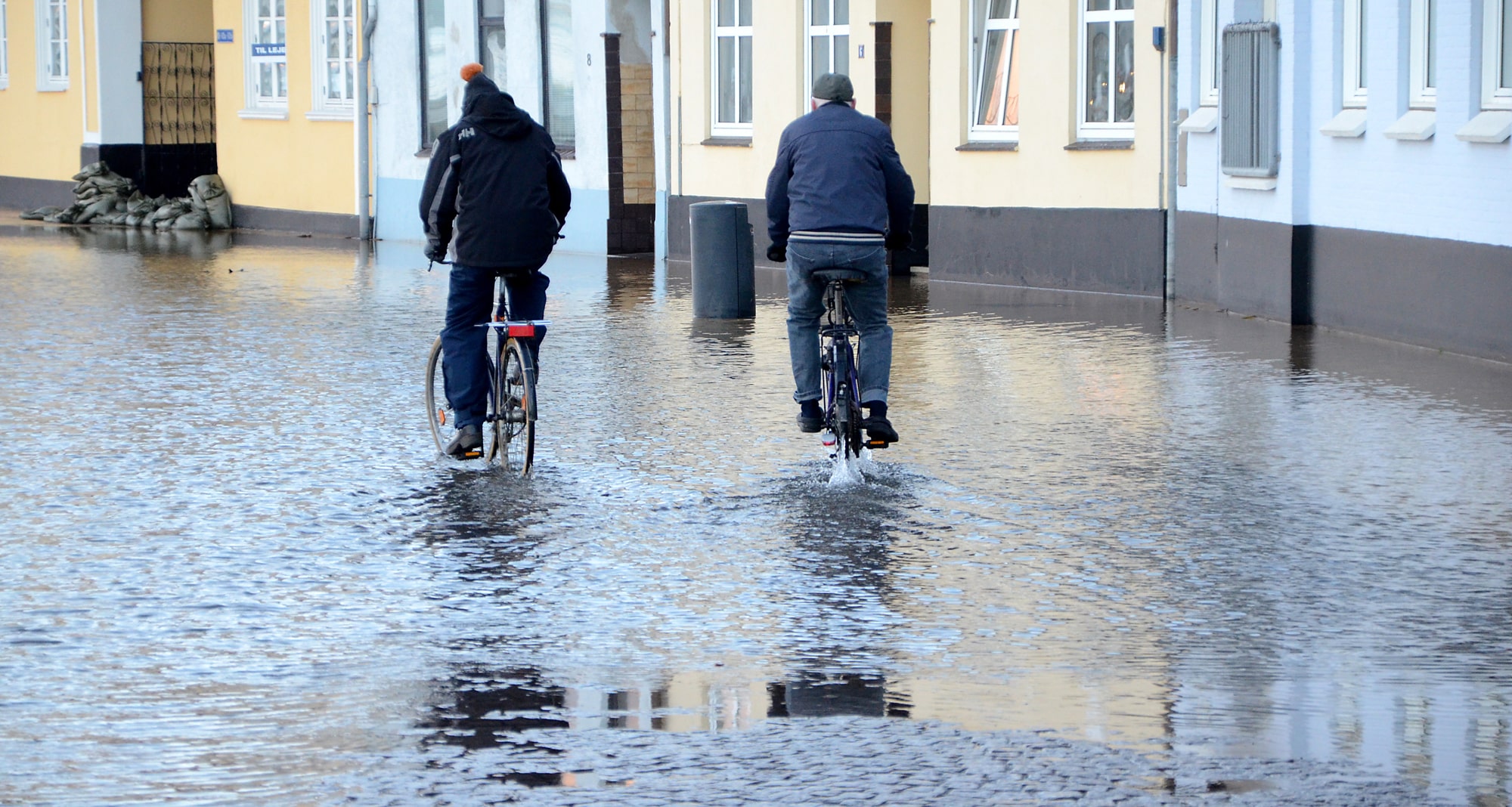 Cyklister på översvämmad gata
